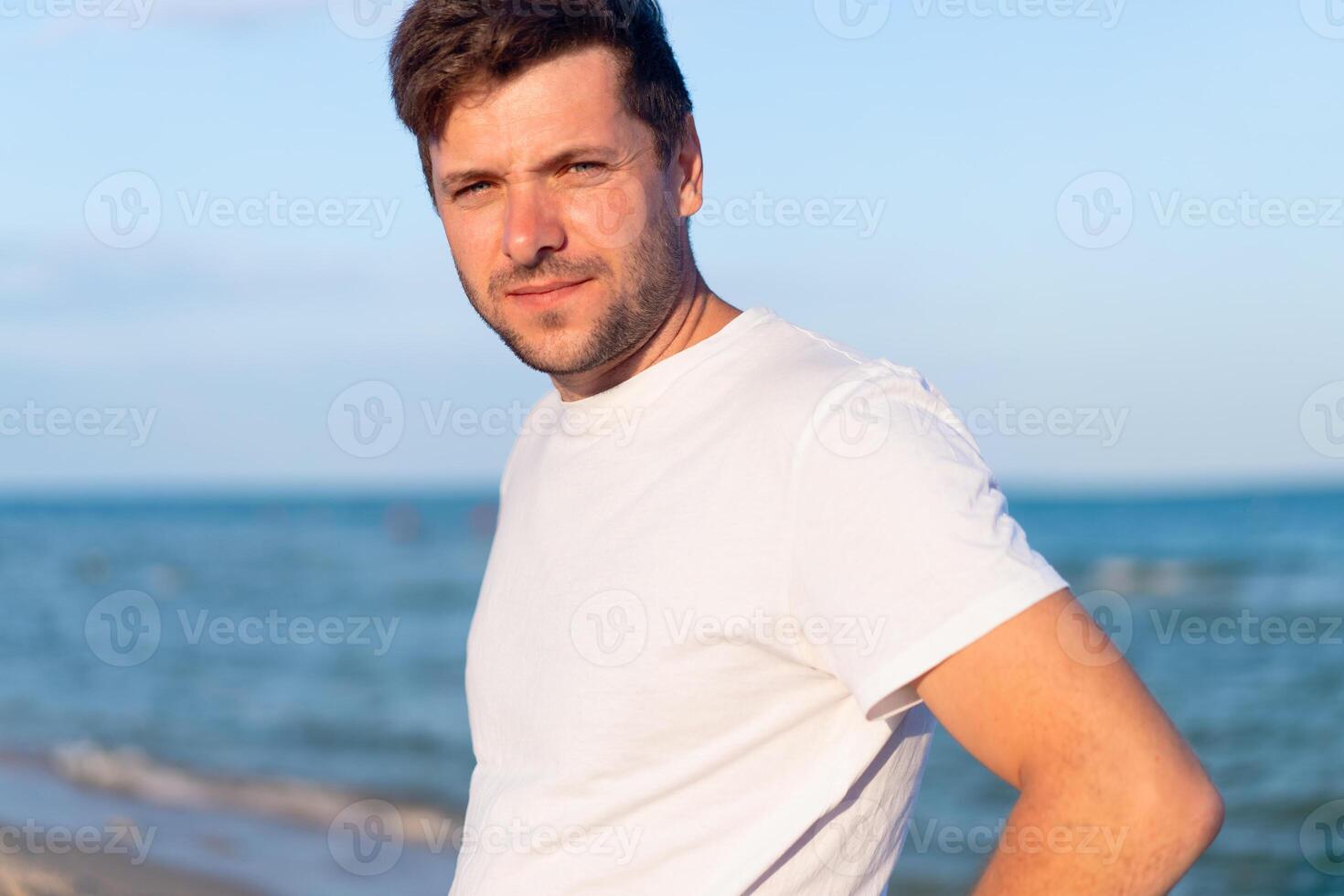 Caucasian man standing on the sea beach dressing white shirt photo