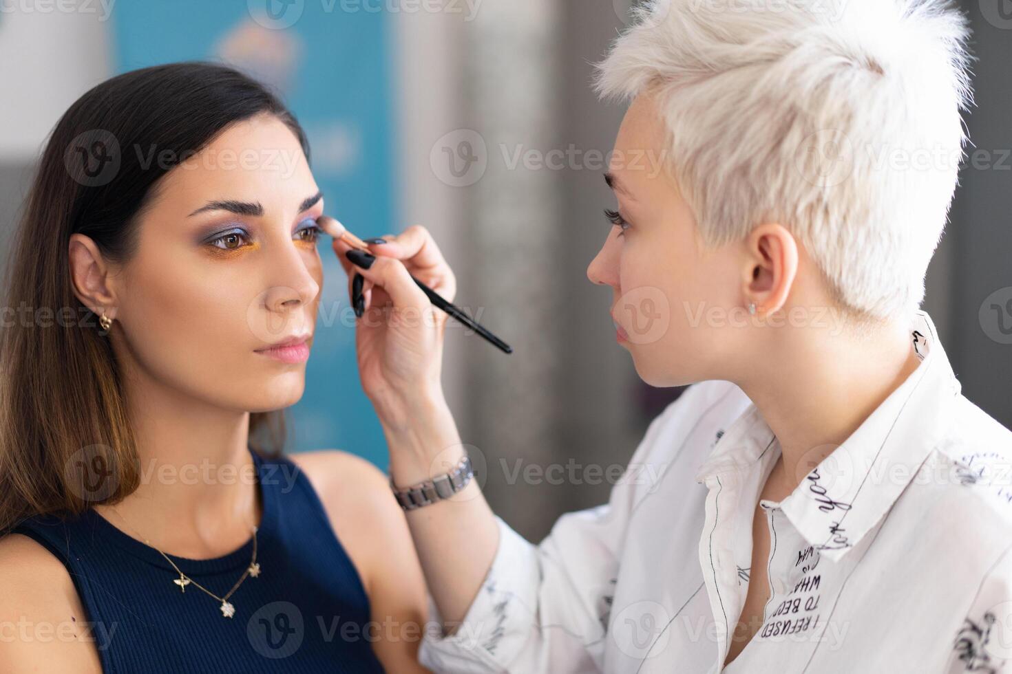 maquillaje artista aplicando brillante base color sombra en del modelo ojo y participación un cáscara con sombra en antecedentes foto