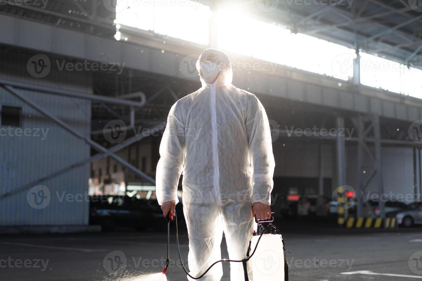 Man dressed white protective overalls spraying surface antibacterial sanitizer sprayer during quarantine photo