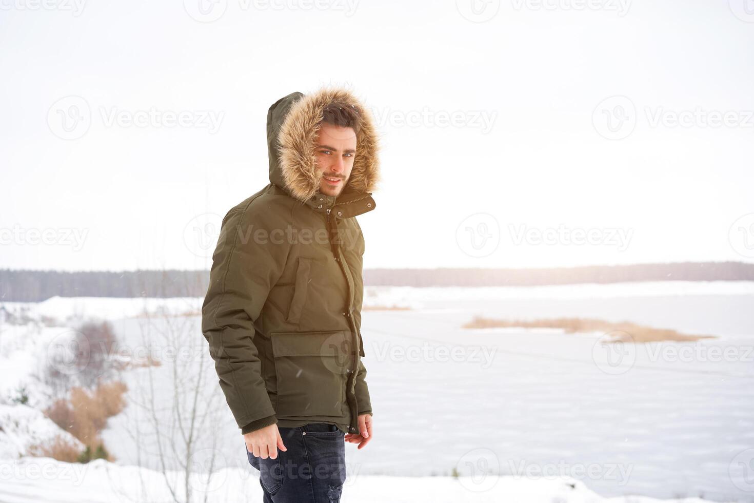 Attractive bearded man standing outdoors in winter season forest. photo