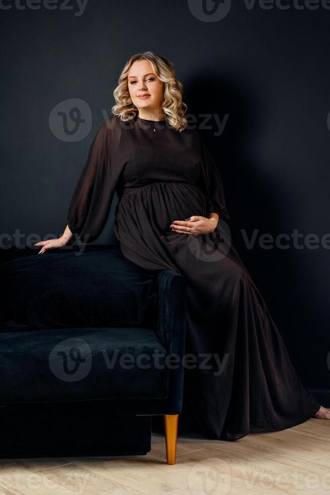 Pregnant Woman Posing In An Elegant black Dress indoors studio black wall background photo