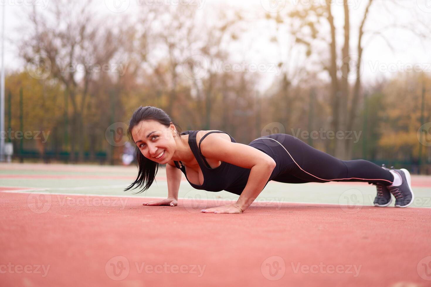 Happy girl doing plank outdoor on playground. Healthy lifestyle. Morning workout positive emotion smiling sportive people photo