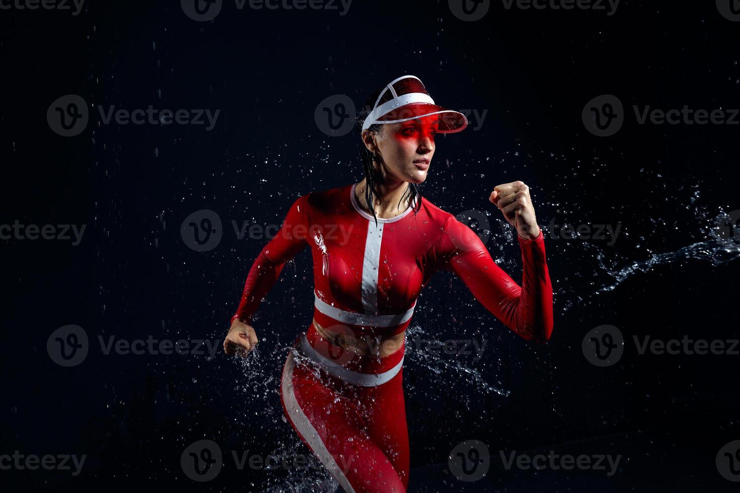 Beautiful young girl in sportswear runing in aqua studio. Drops of water spread about her fitness body. The perfect figure on the background of water splashes. Bad weather for sport photo