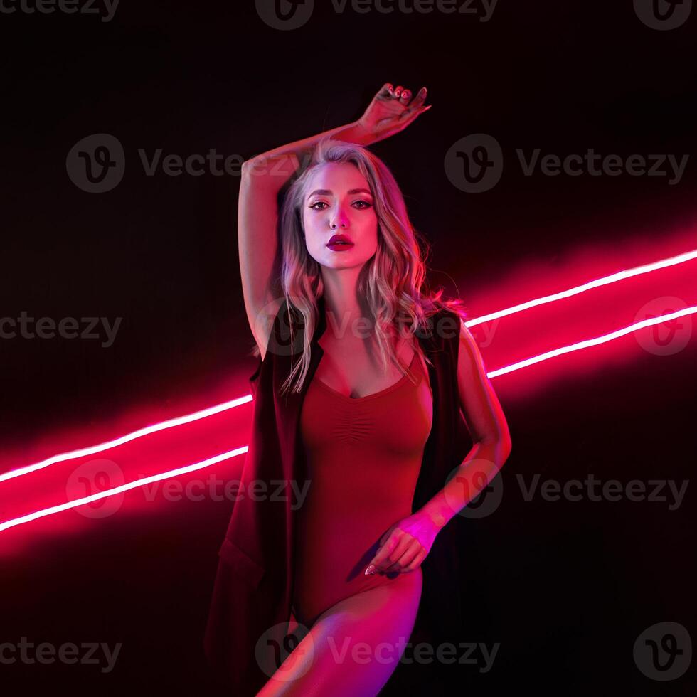 Fashion art photo of elegant model in seductive red swimsuit with light neon colored club spotlights Night club sexy concept