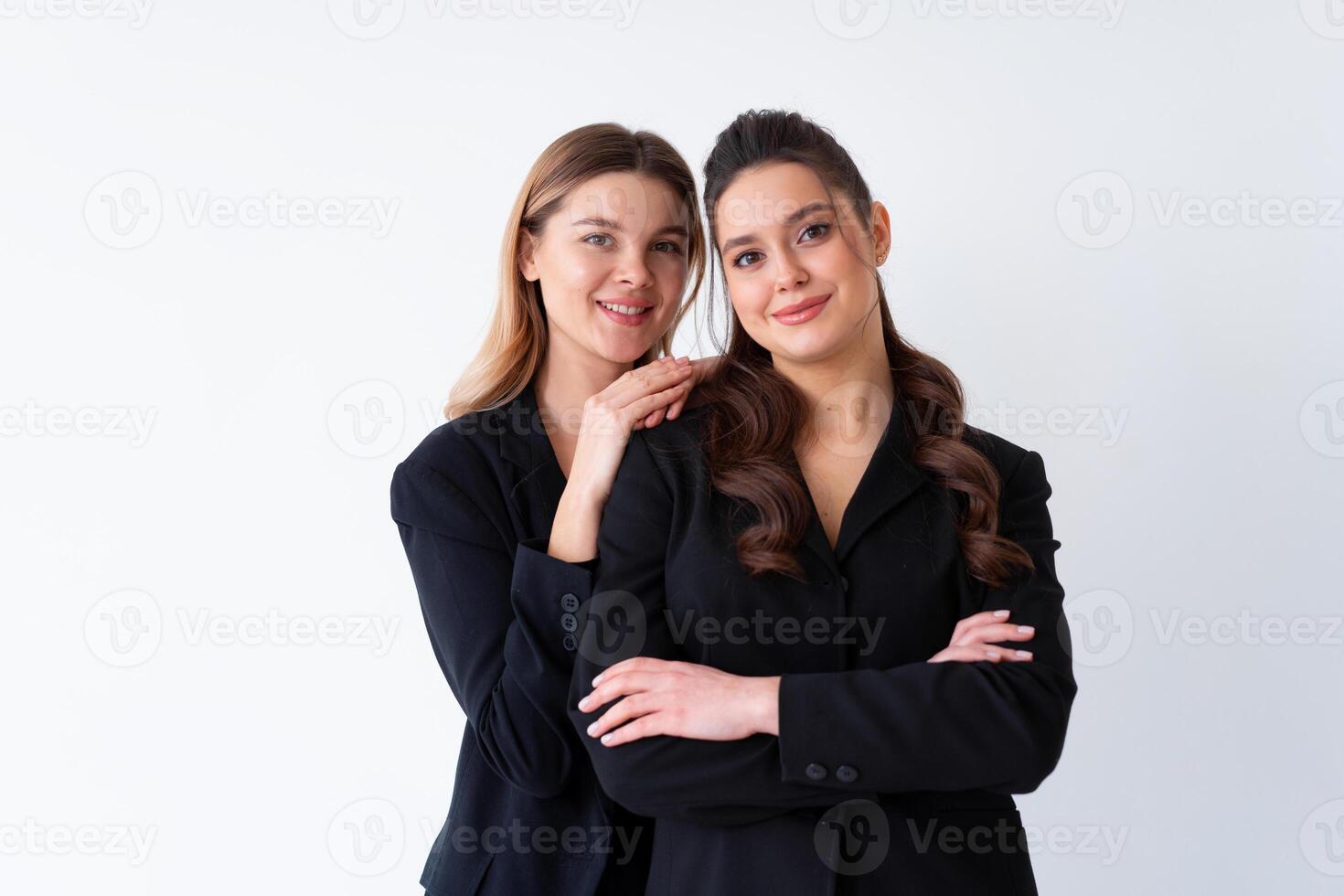 Concept of partnership in business. Two Young businesswoman dressed black formal suit standing studio isolated white background. photo