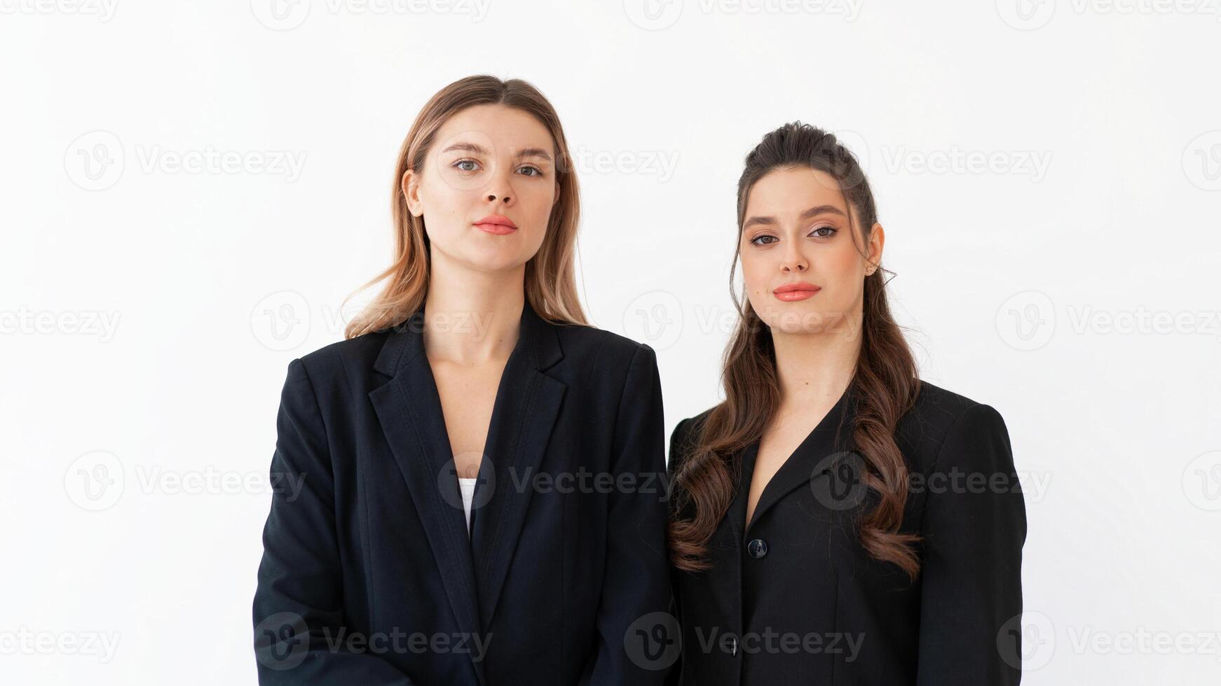 Concept of partnership in business. Two Young businesswoman dressed black formal suit standing studio isolated white background. photo
