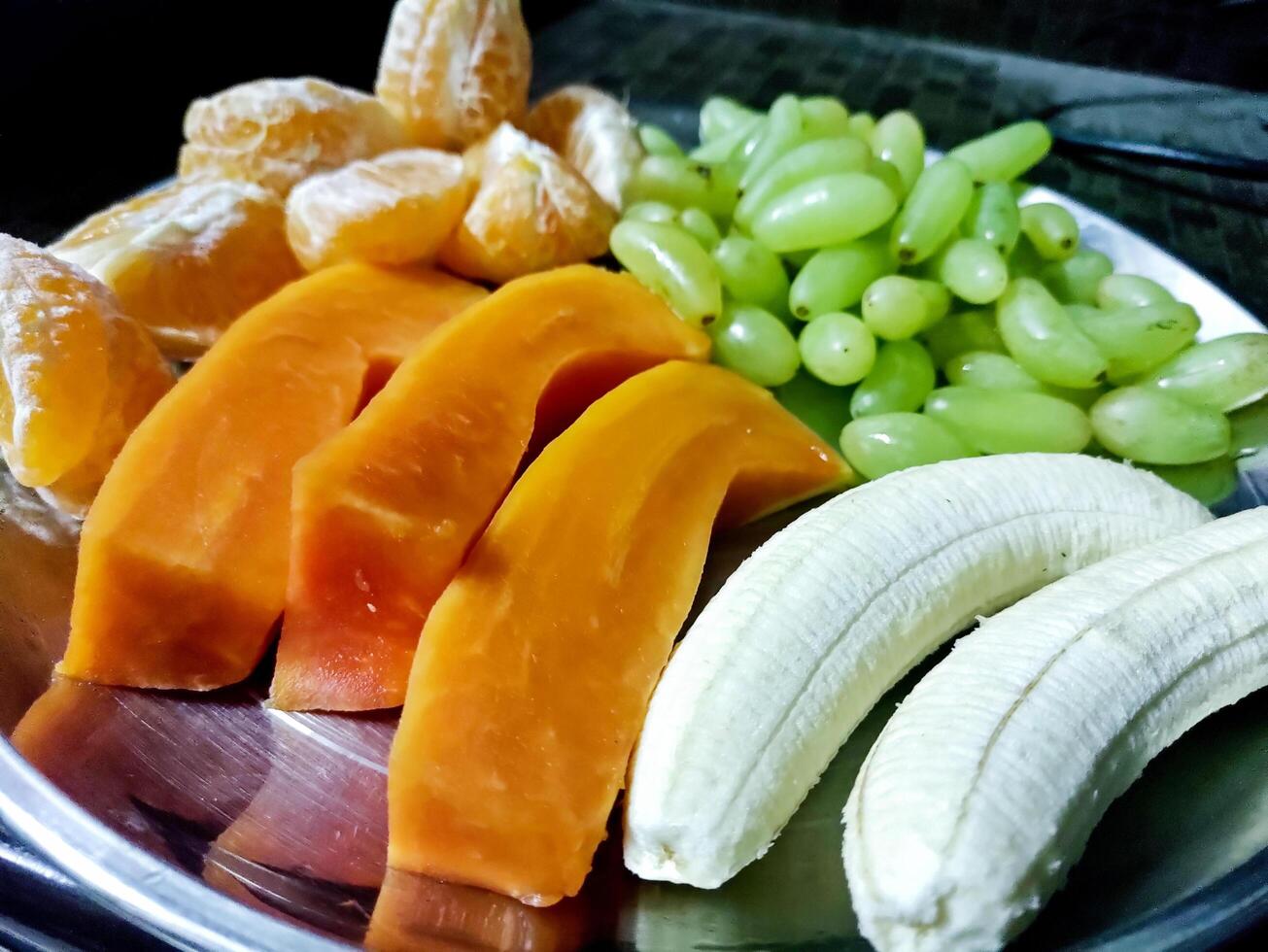 Plate with different fruits on kitchen table photo