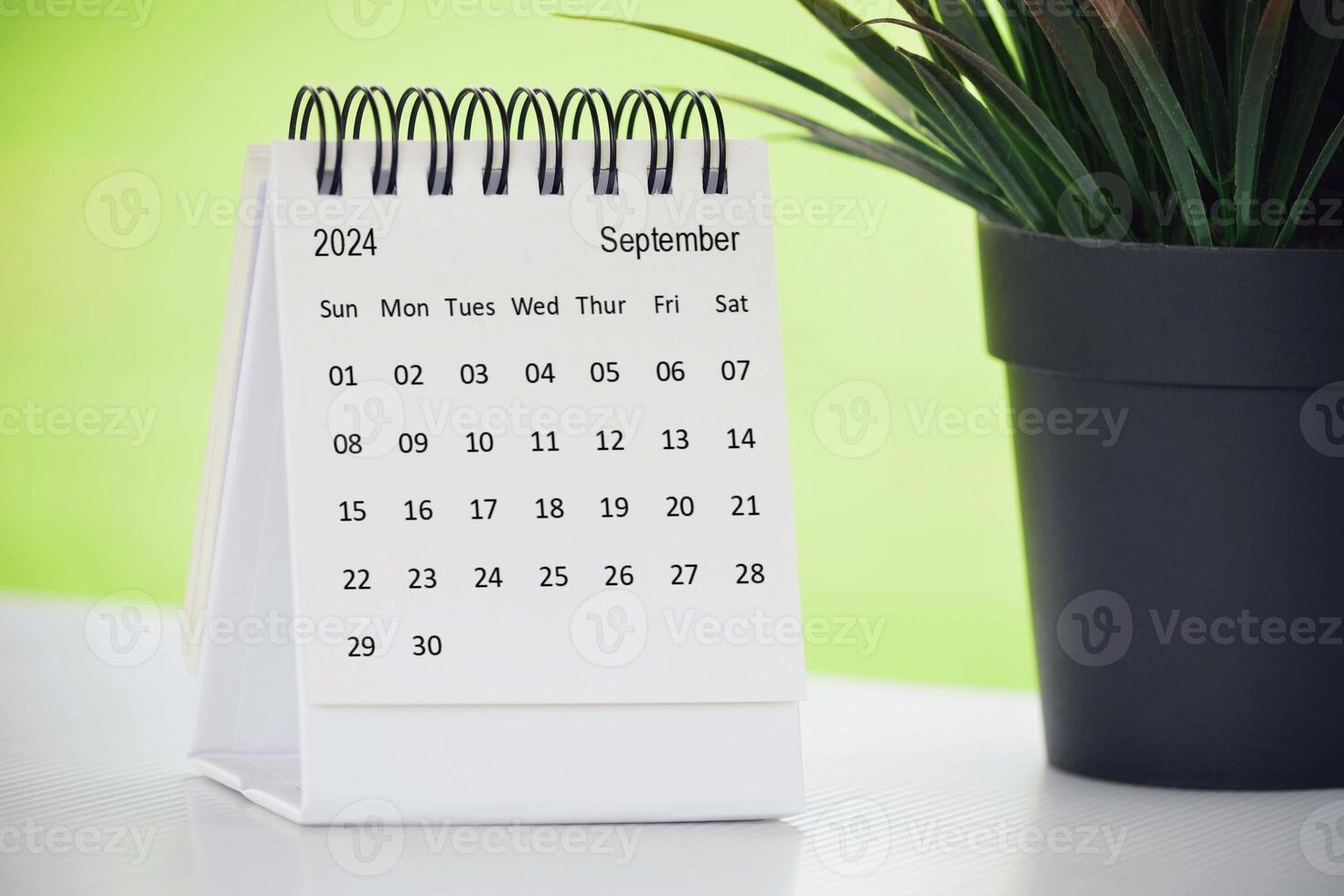 septiembre 2024 escritorio calendario con en conserva planta en un escritorio con verde antecedentes. foto