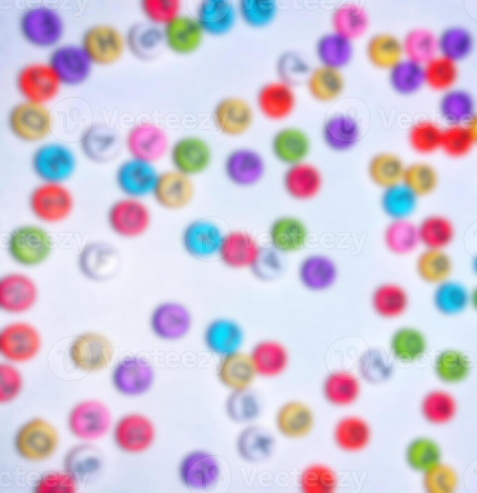 Blurry out of focus photo of alphabet, colorful round numbers, colorful round letters on white background