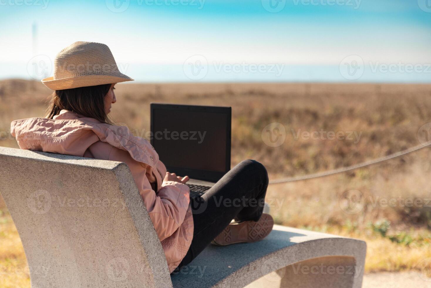 Woman with laptop computer sitting in front of the beach in Barcelona. photo