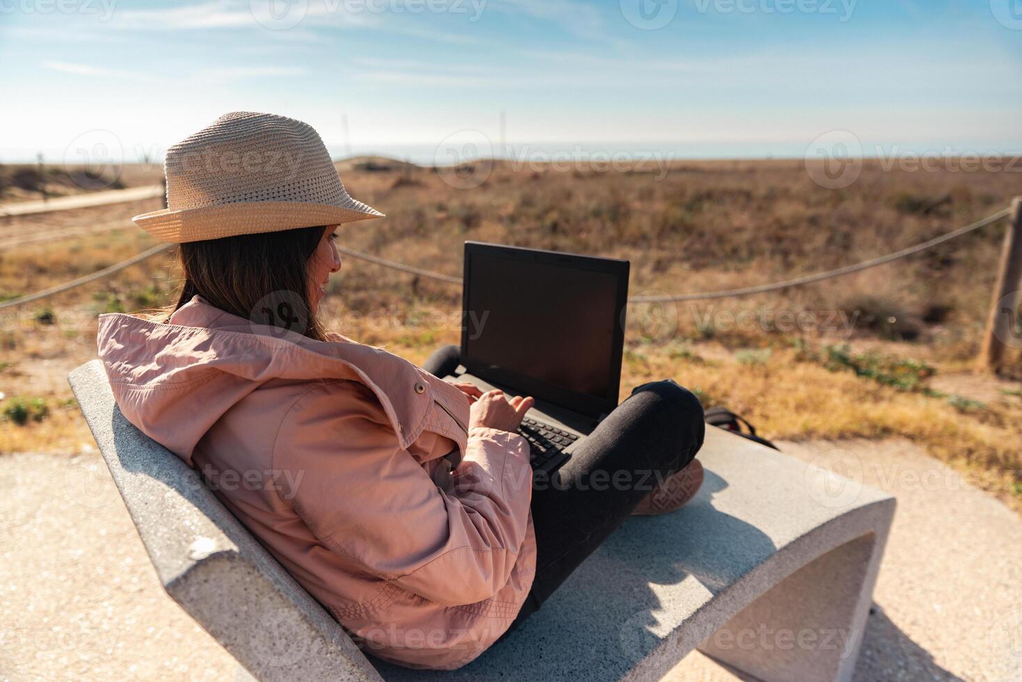 Woman with laptop computer sitting in front of the beach in Barcelona. photo