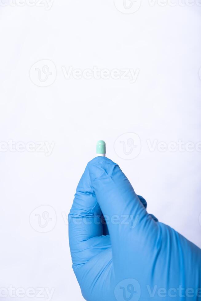 Hand with a blue latex glove, clutching a tablet. photo