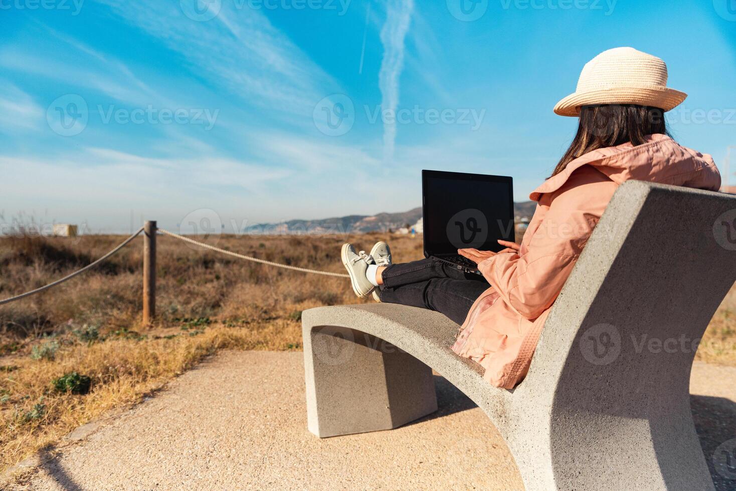 Traveler with her laptop sitting on the Mediterranean coast of Barcelona. photo