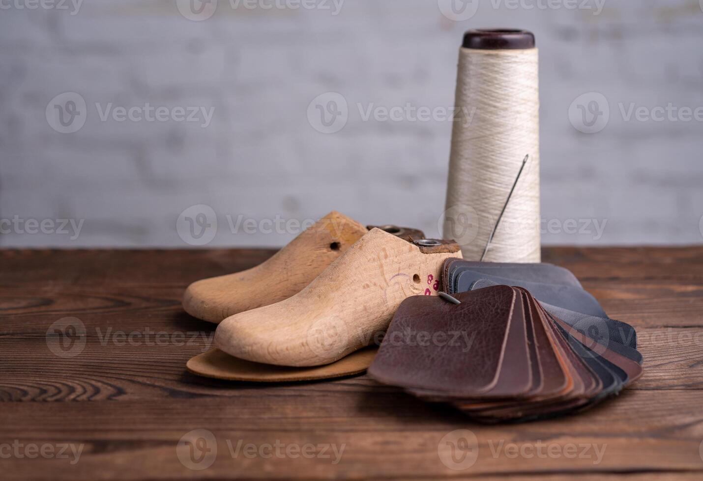 Leather samples for shoes and wooden shoe last on dark wooden table. photo