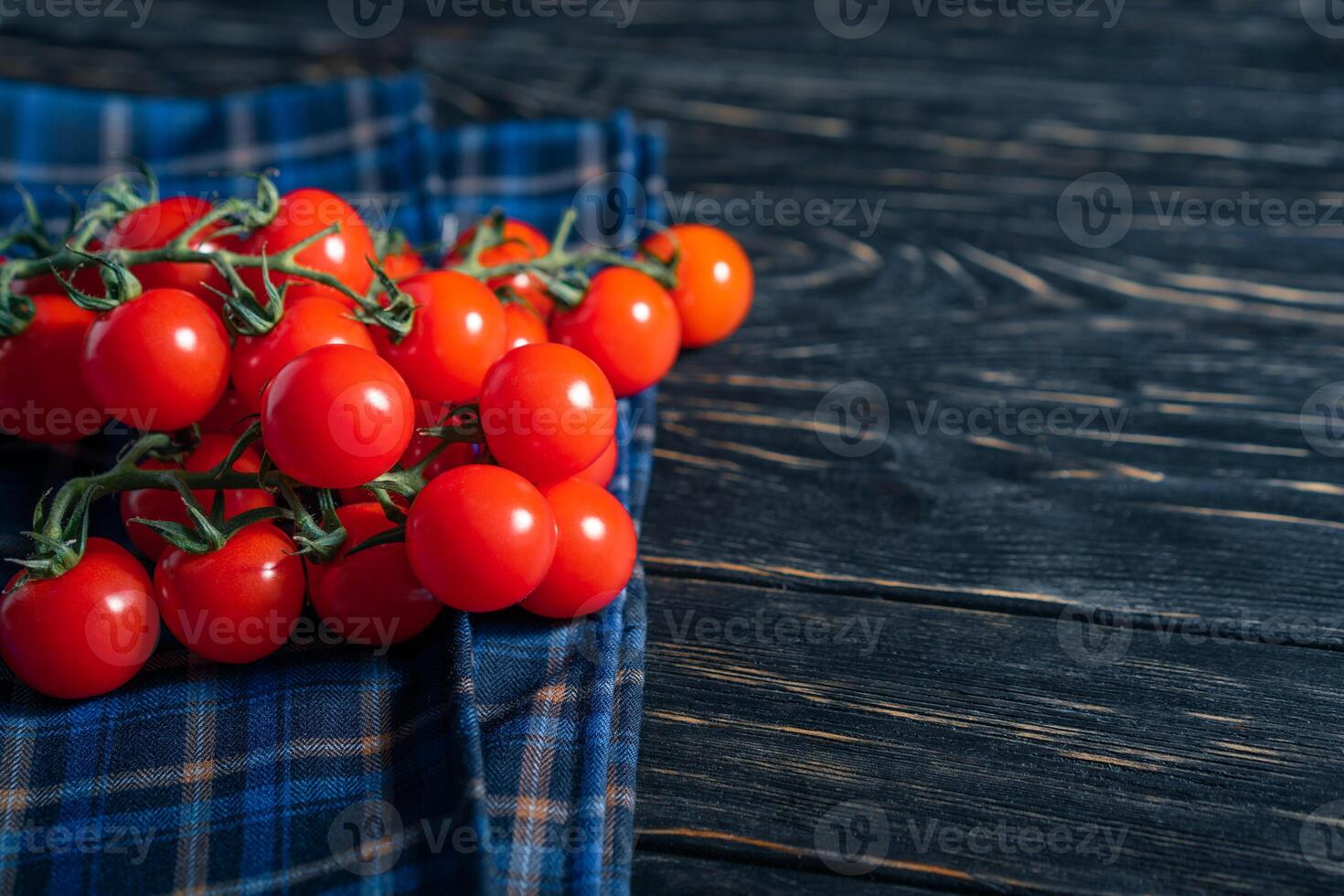 Cherry tomatoes in the checkered cloth serviette on the wooden table photo