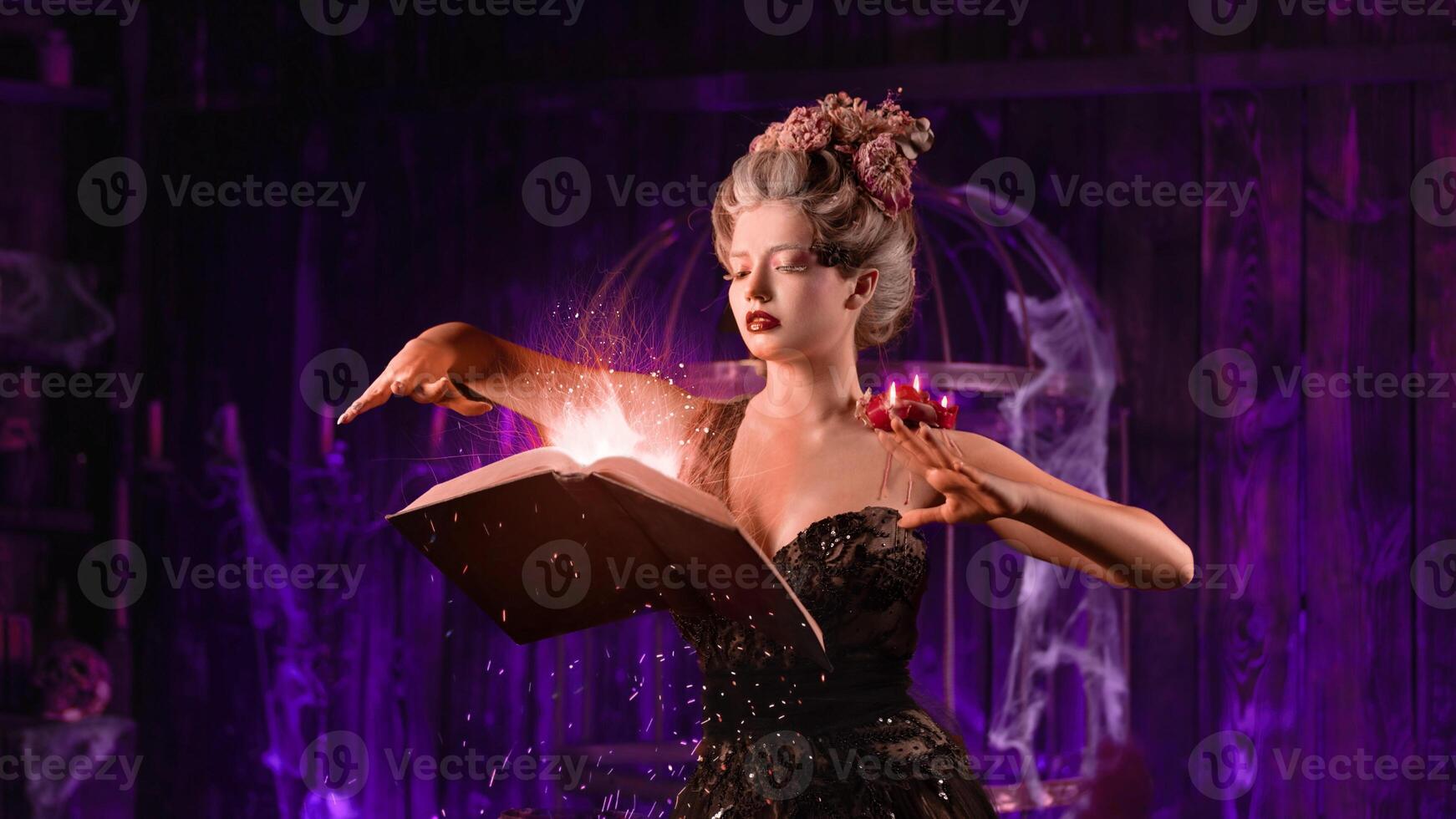 Charming woman witch flowers in hair vintage black dress with book of spell in the old castle. Halloween. Celebration. photo