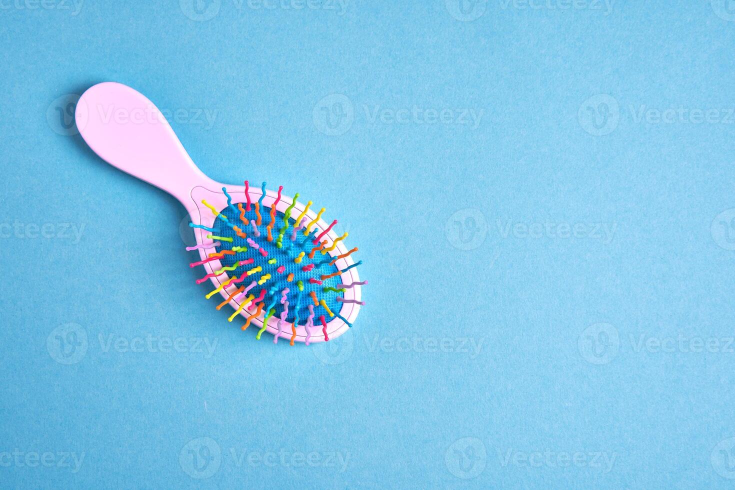 Funny baby comb with multi-colored plastic wavy bristles lies on a blue background. photo