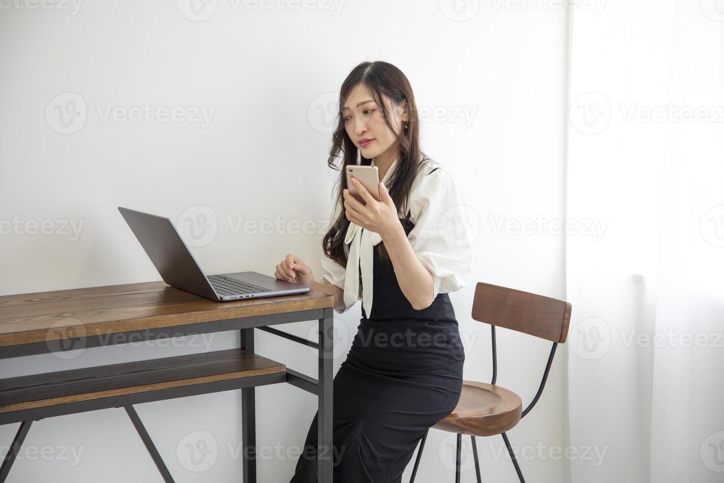A Japanese woman checking smartphone by remote work in the home office photo