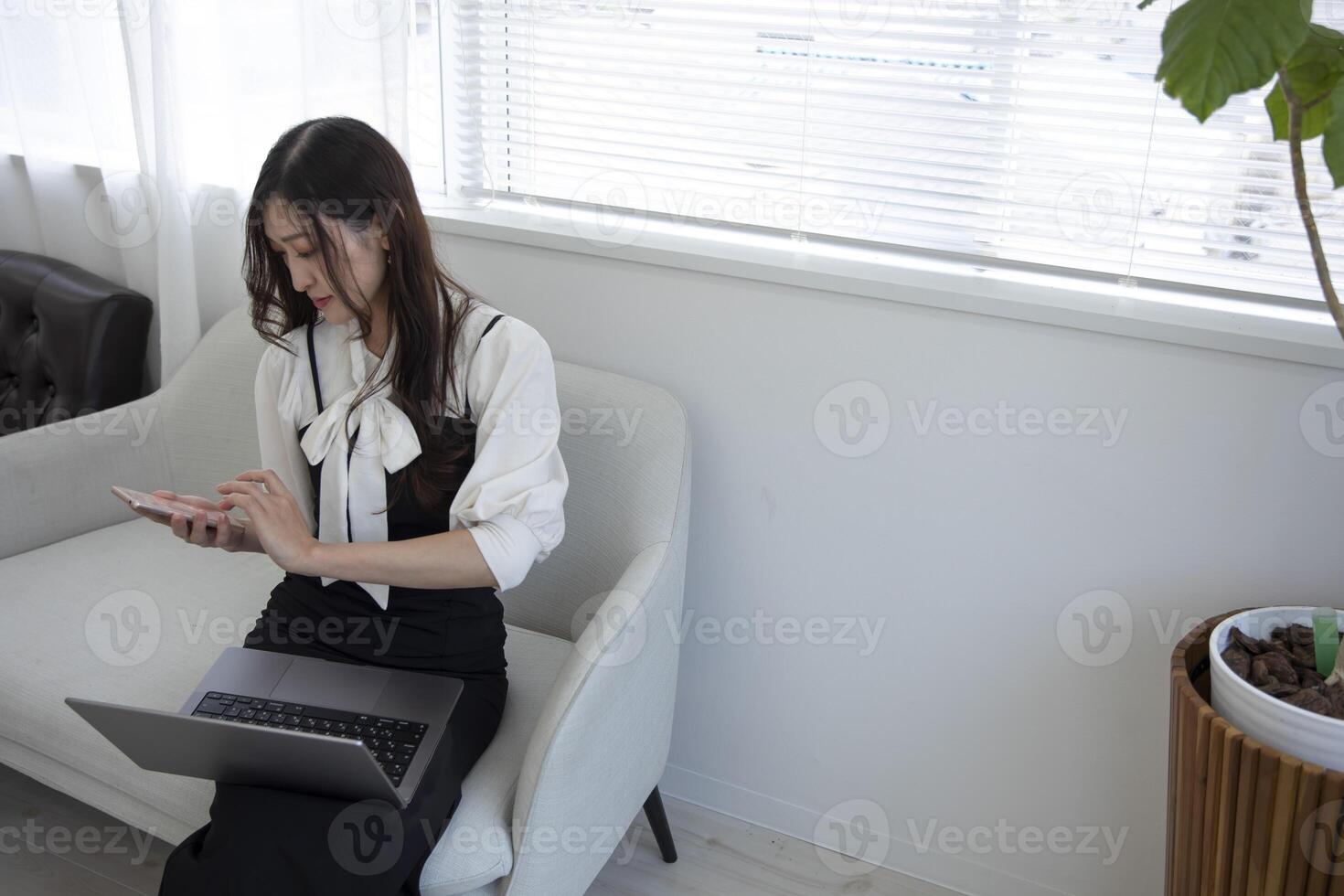 un japonés mujer comprobación teléfono inteligente por remoto trabajo en el hogar oficina foto