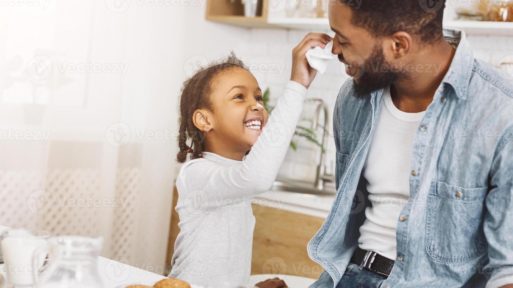 Happy black man and his daughter having breakfast photo