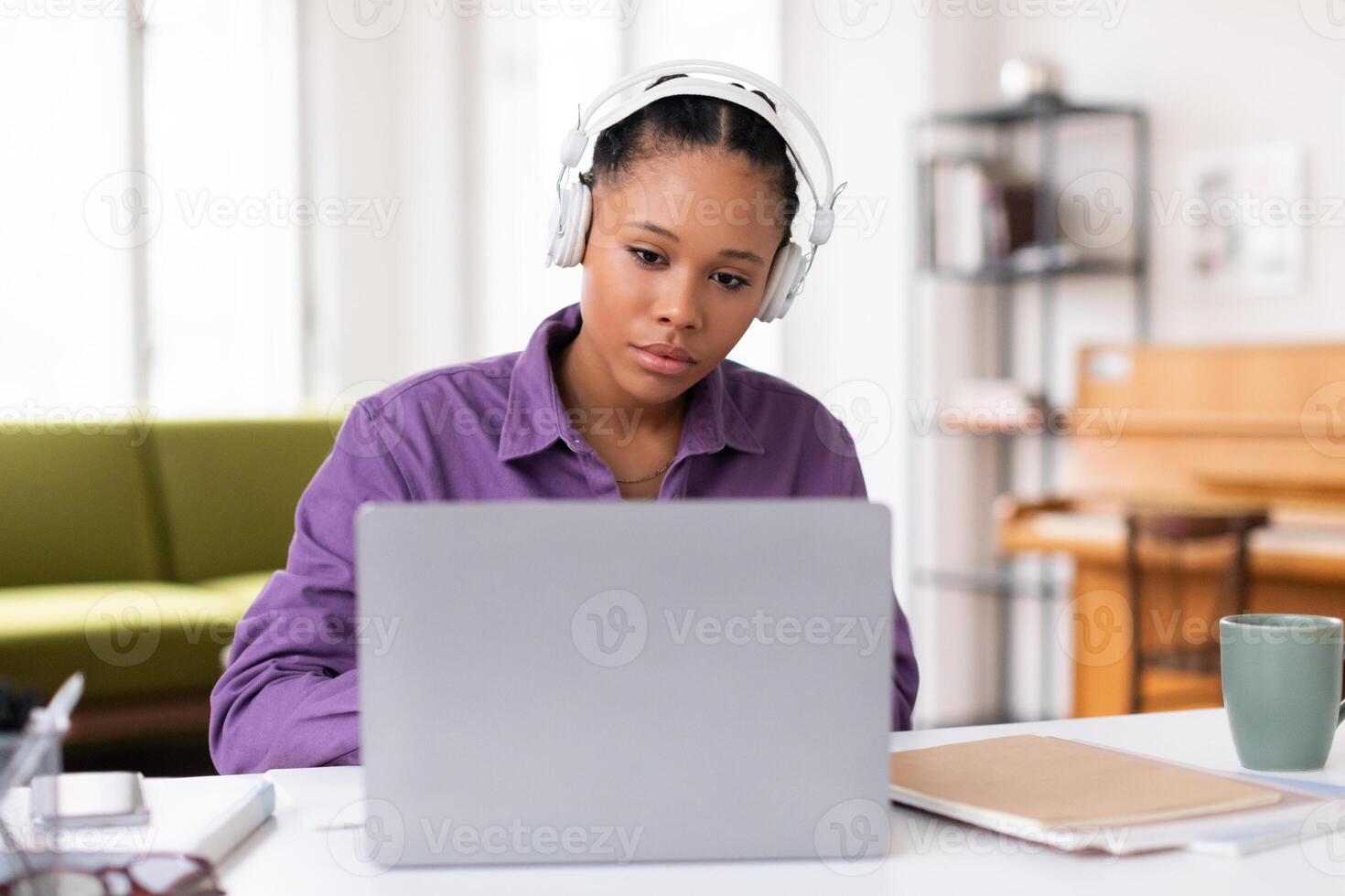 Focused black female student with headphones using laptop photo