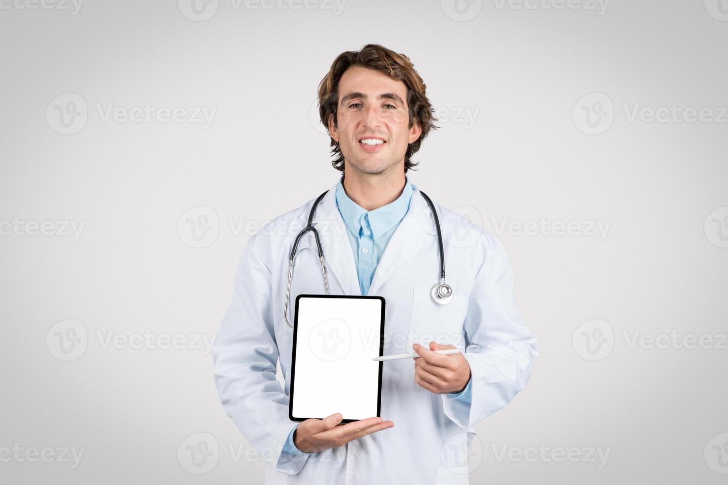 Cheerful male doctor presenting blank tablet screen photo