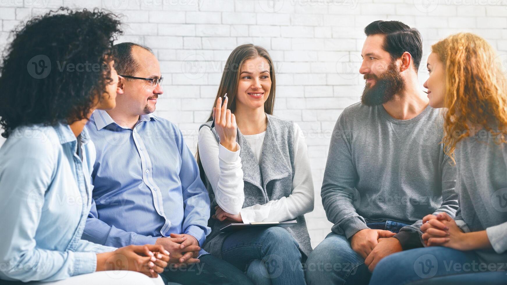 Smiling Psychologist Talking To Group Members At Therapy Session In Rehab photo