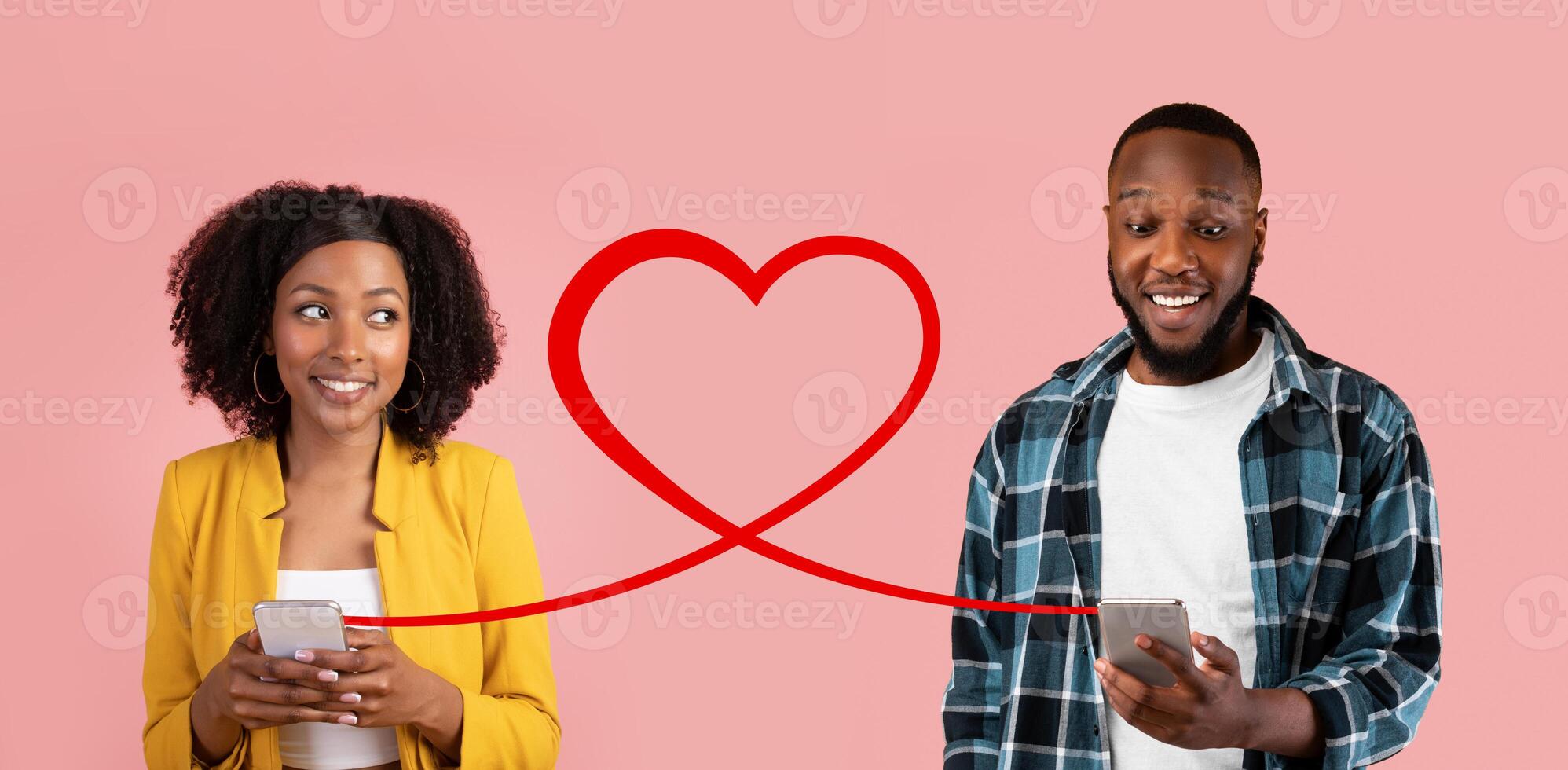 A smiling woman in a yellow blazer and a man in a plaid shirt hold smartphones, with a red heart graphic photo