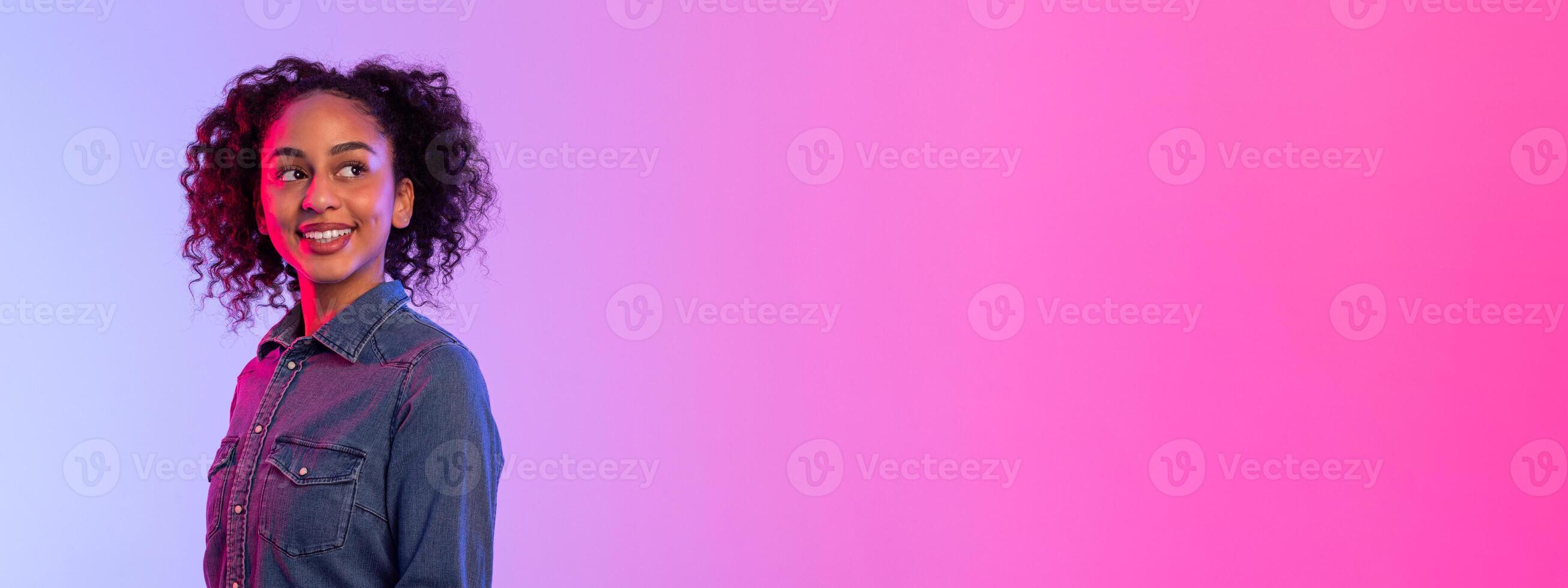 Cheerful african american lady looking at free space on vibrant pink to purple gradient photo