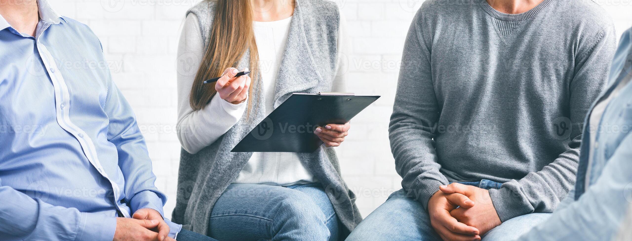 Psychotherapist talking with patients during group therapy session and taking notes photo