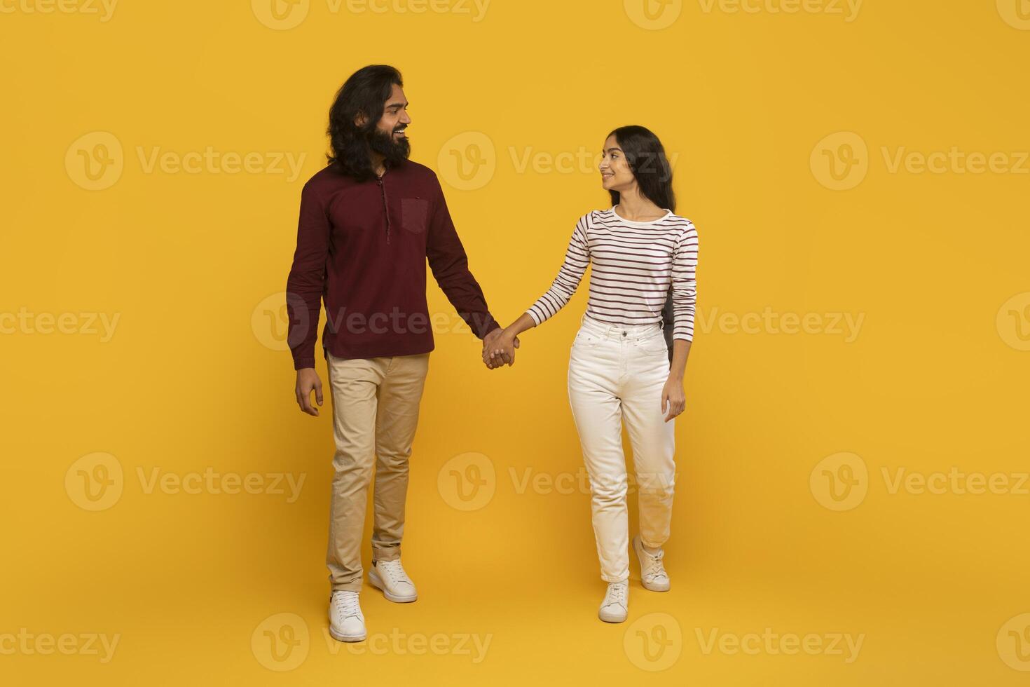 Couple walking hand in hand, yellow backdrop photo
