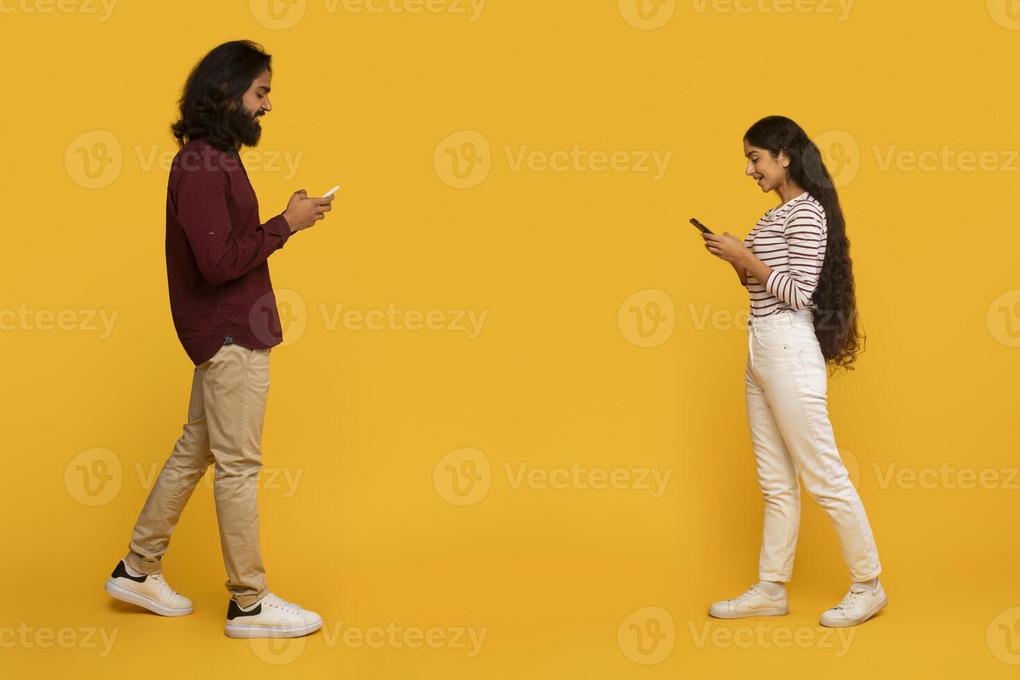 Two people standing back to back texting photo