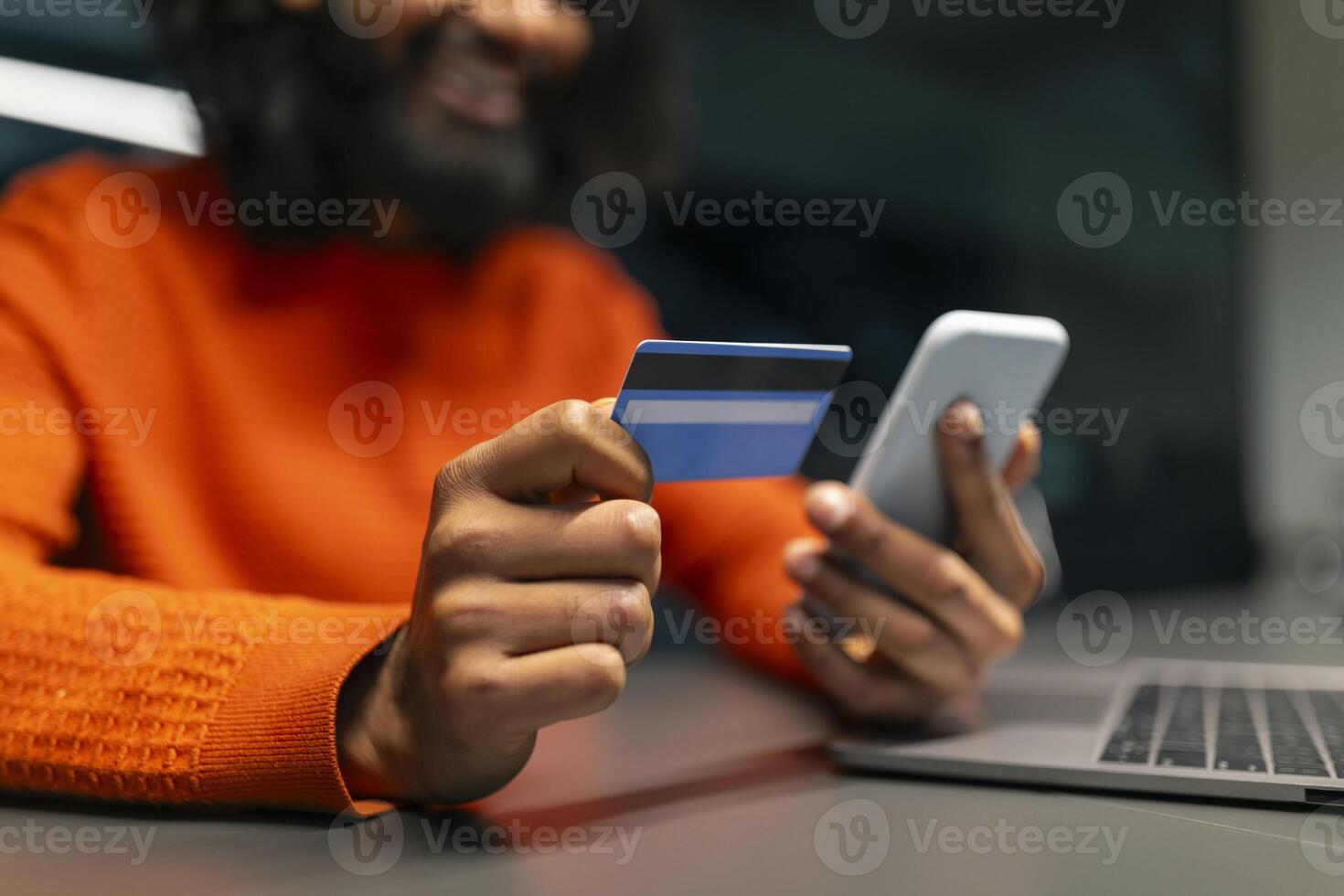 Man smiling holding credit card and phone photo