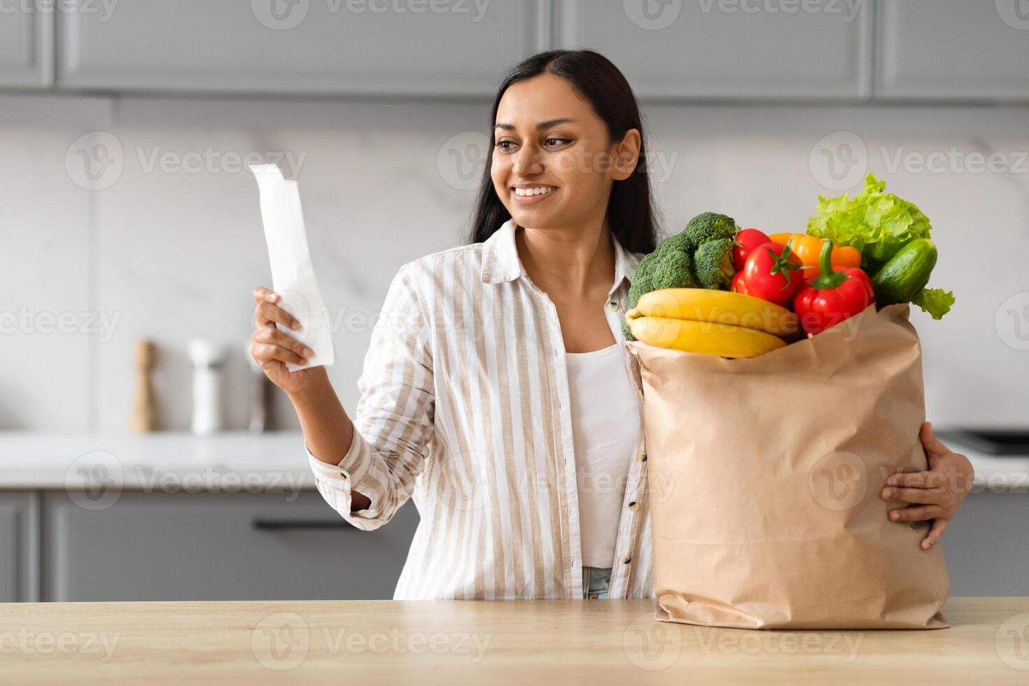 contento indio mujer con bolso lleno de comida comprobación cuenta foto