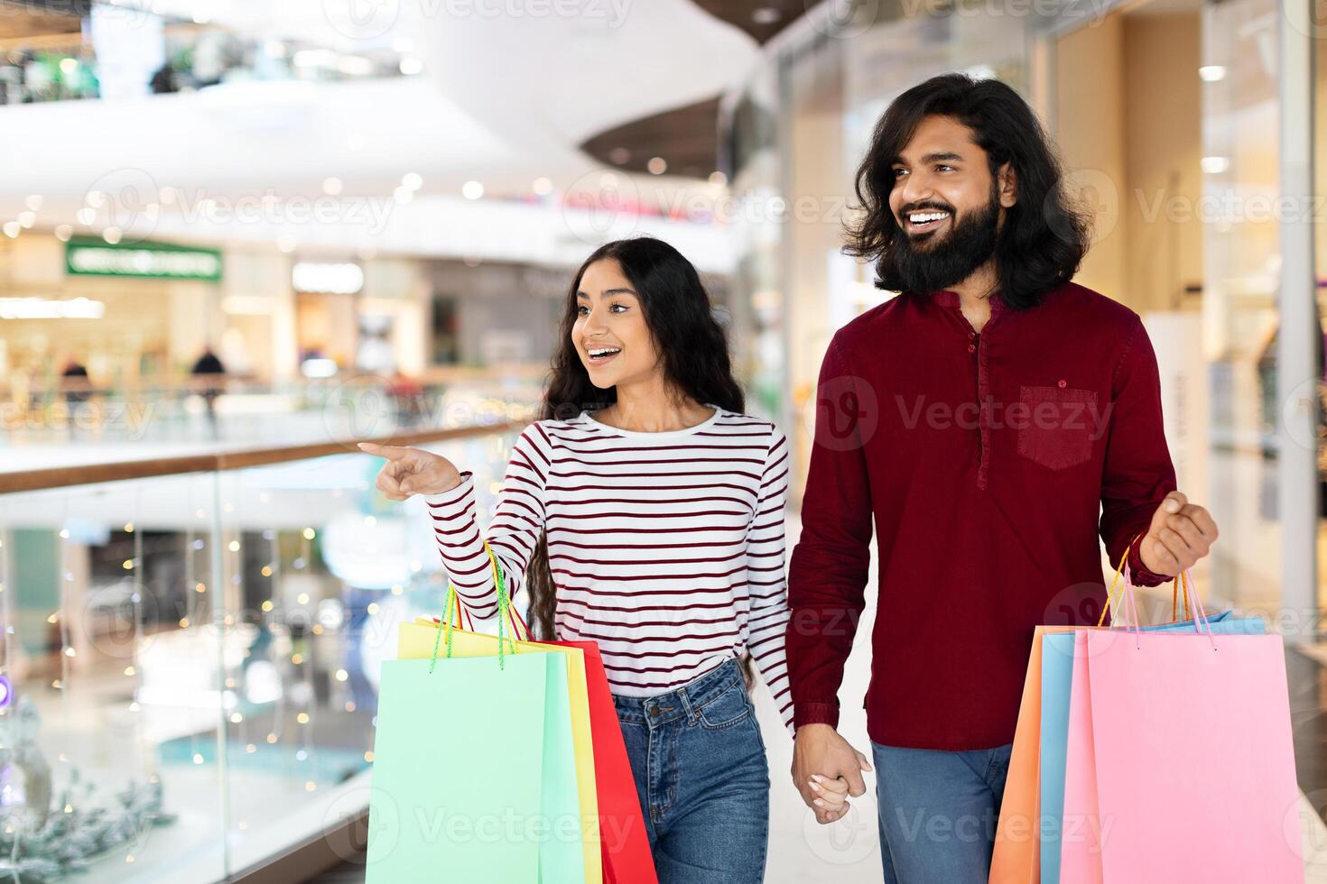 Positive young indian couple carrying purchases, copy space photo