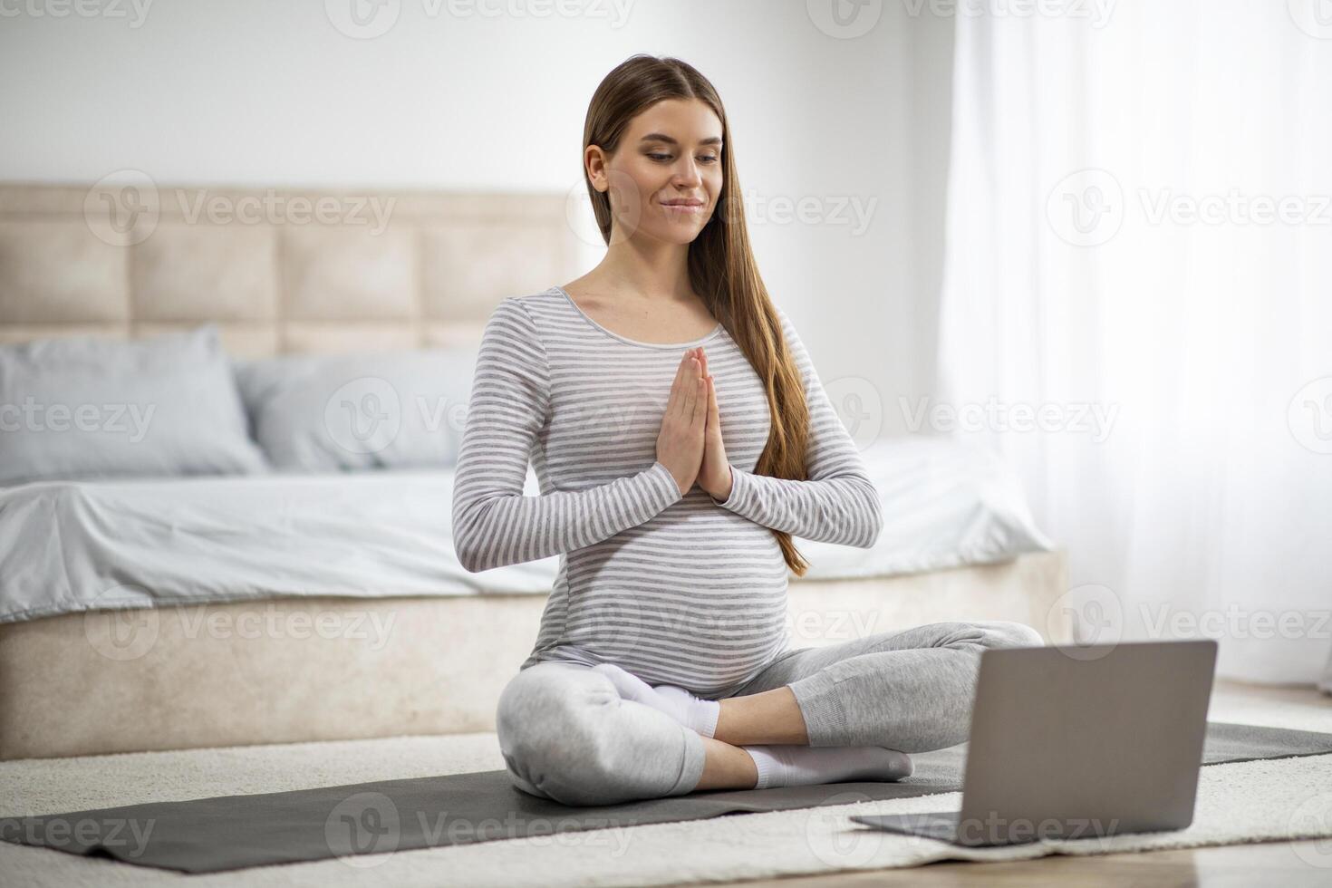 Calm Young Pregnant Woman Having Online Yoga Lesson With Laptop At Home photo