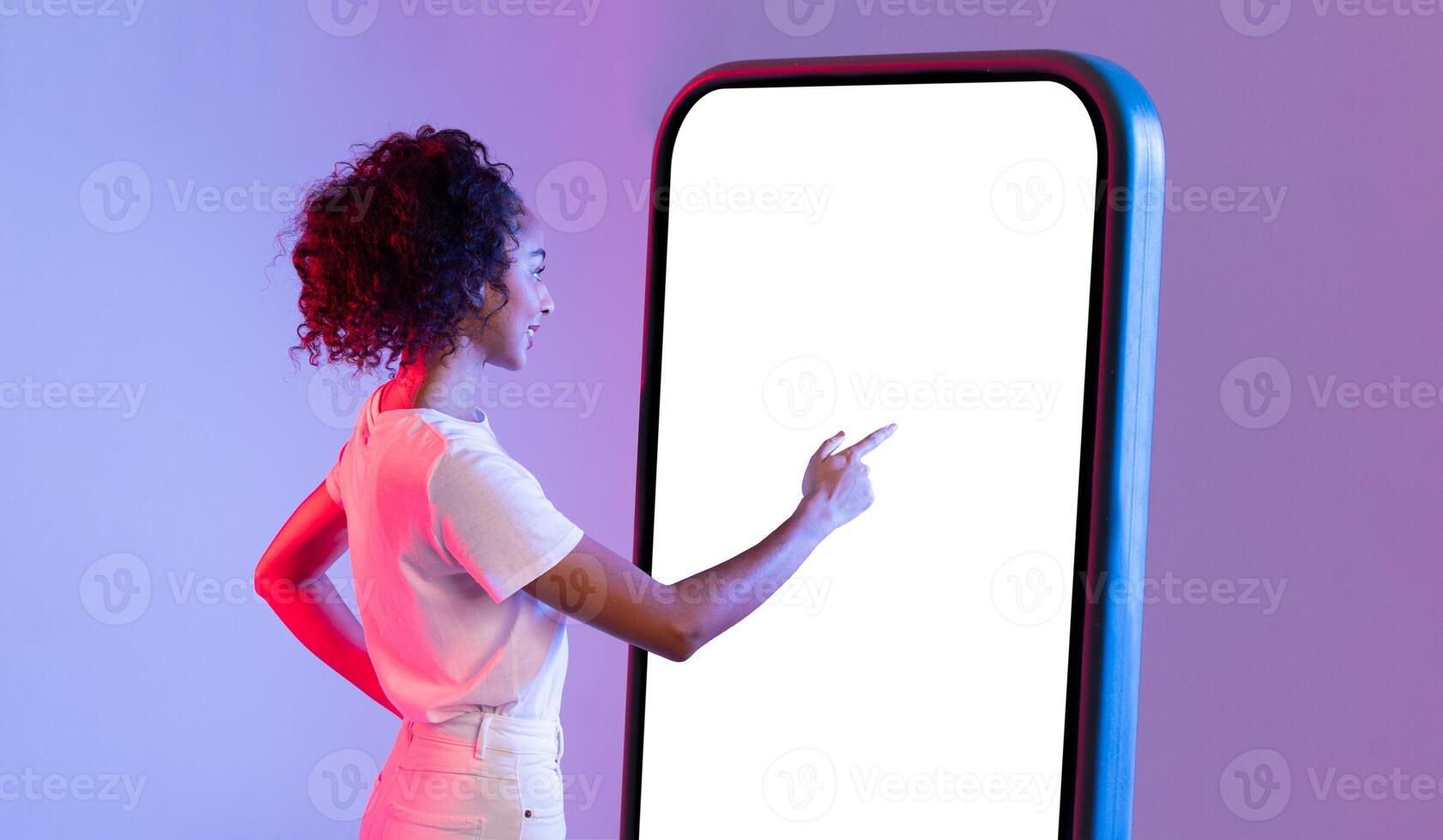 Black lady interacting with large smartphone screen on gradient backdrop photo