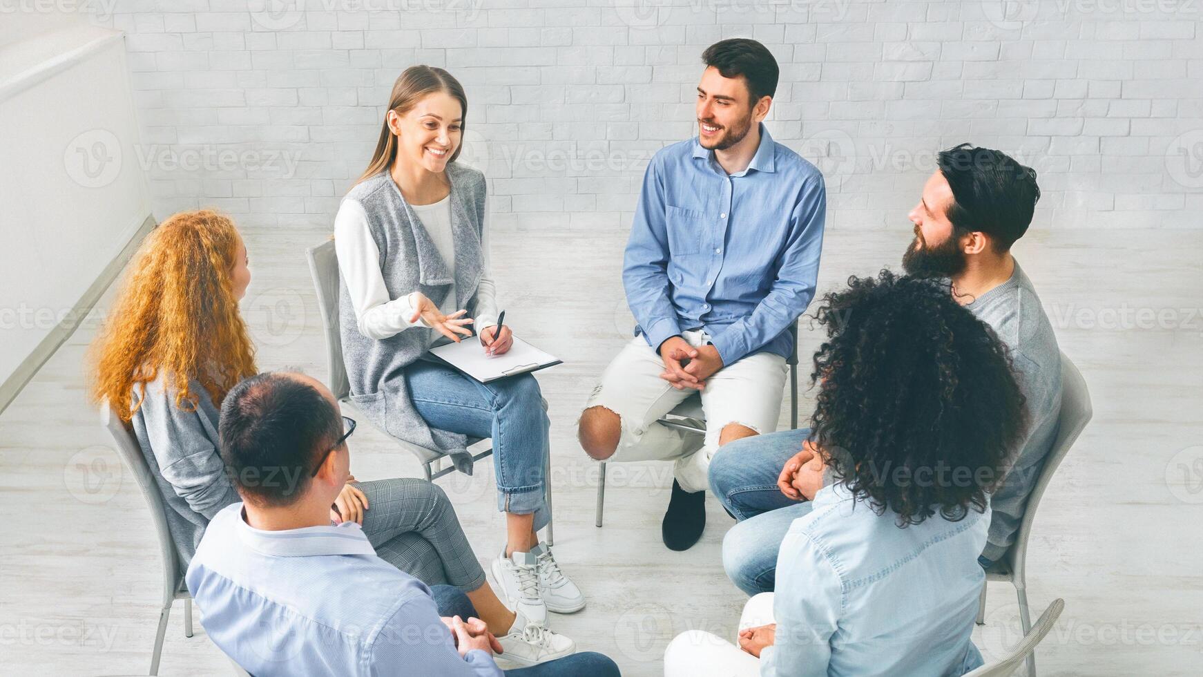 Diverse happy people sitting in trust circle on therapy session photo