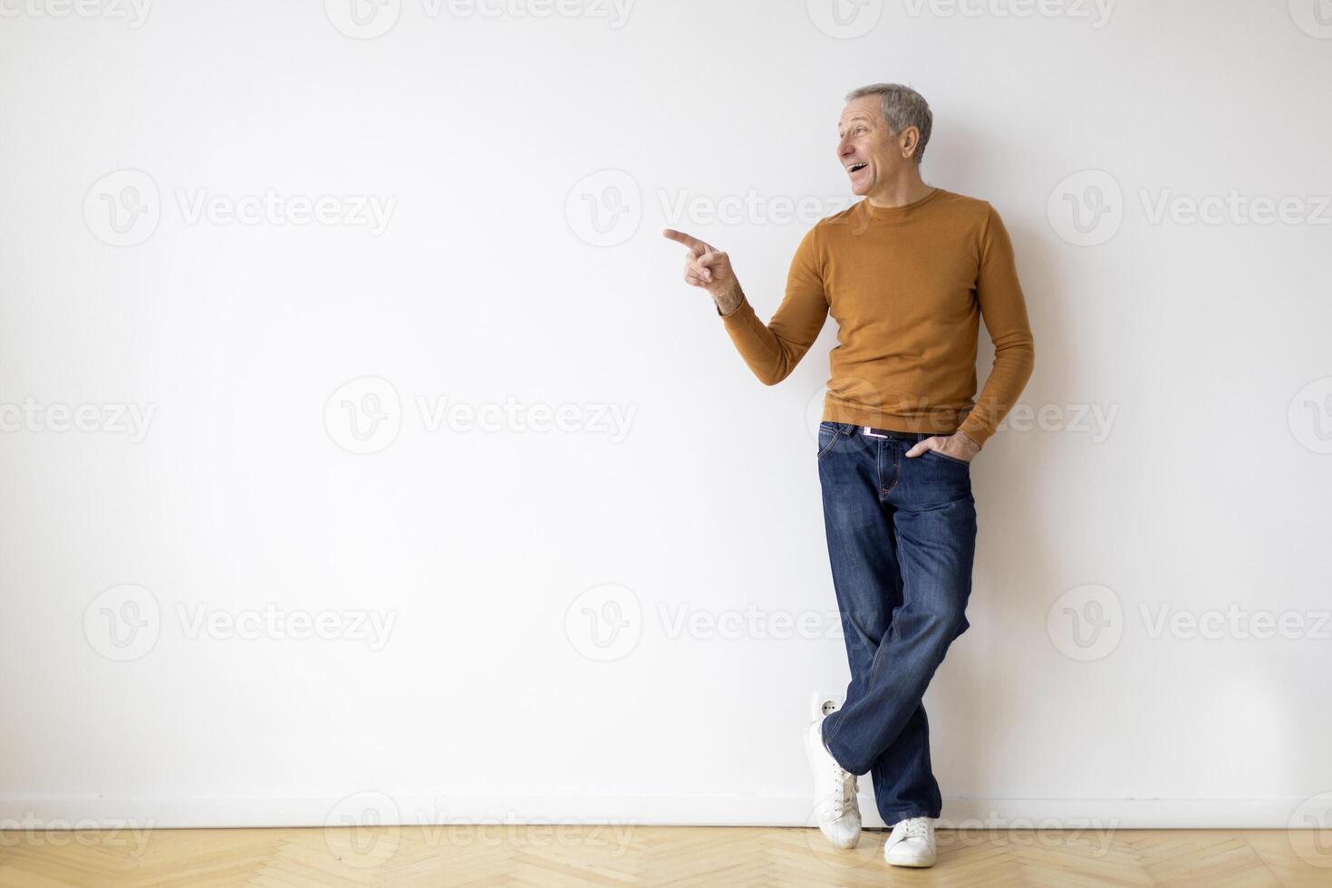 Man in orange sweater pointing to side photo