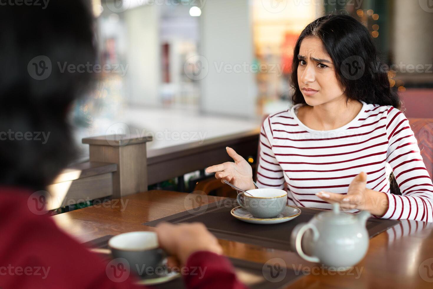 Irritated young indian lady looking at her boyfriend with doubt photo