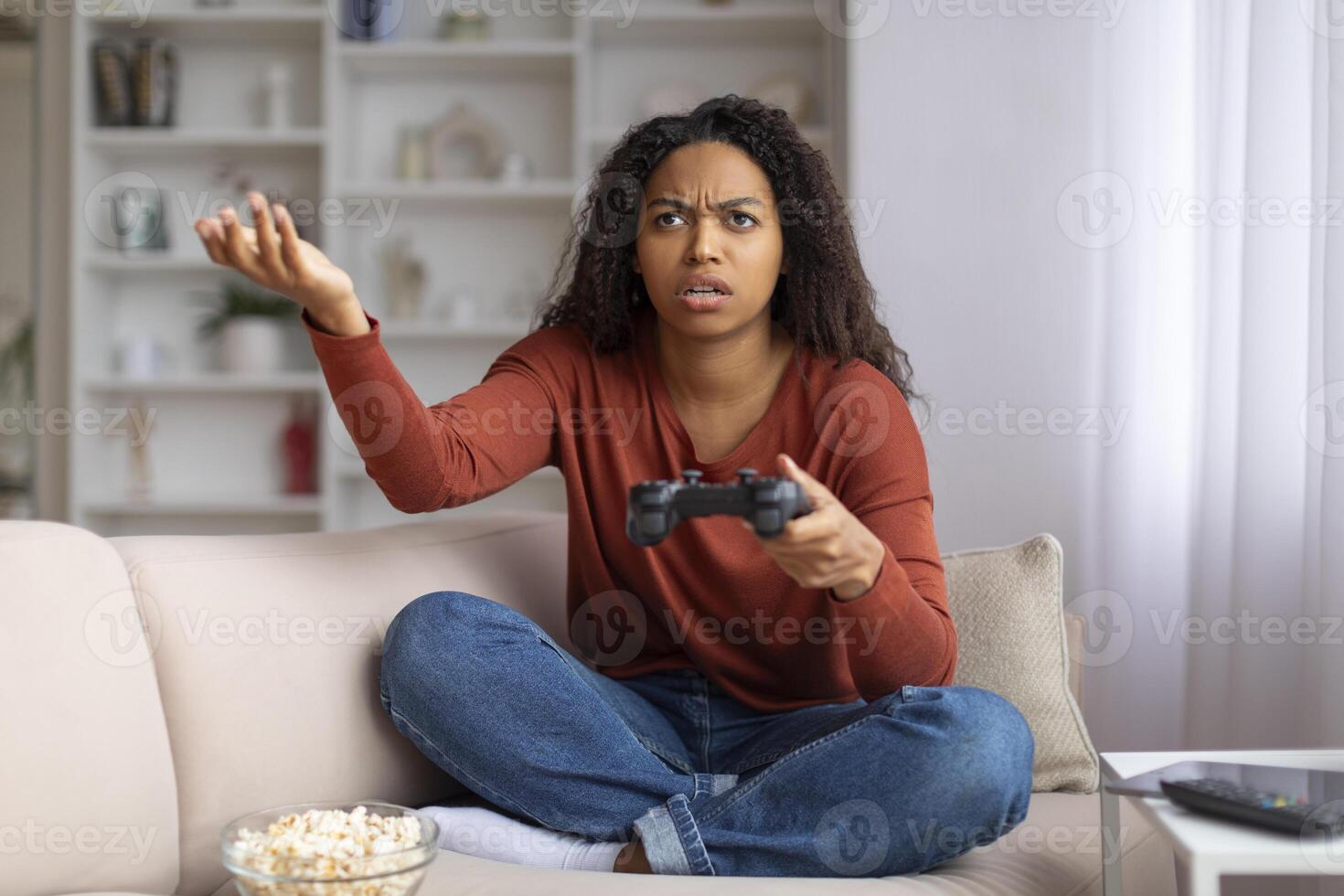 estresado negro mujer con palanca de mando en mano sentado en sofá a hogar foto