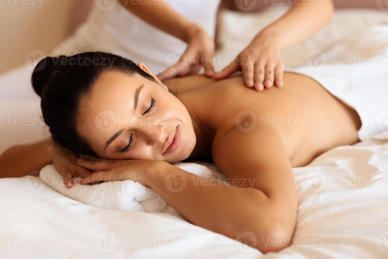 woman enjoying massage and calming touch of masseuse's hands indoor photo