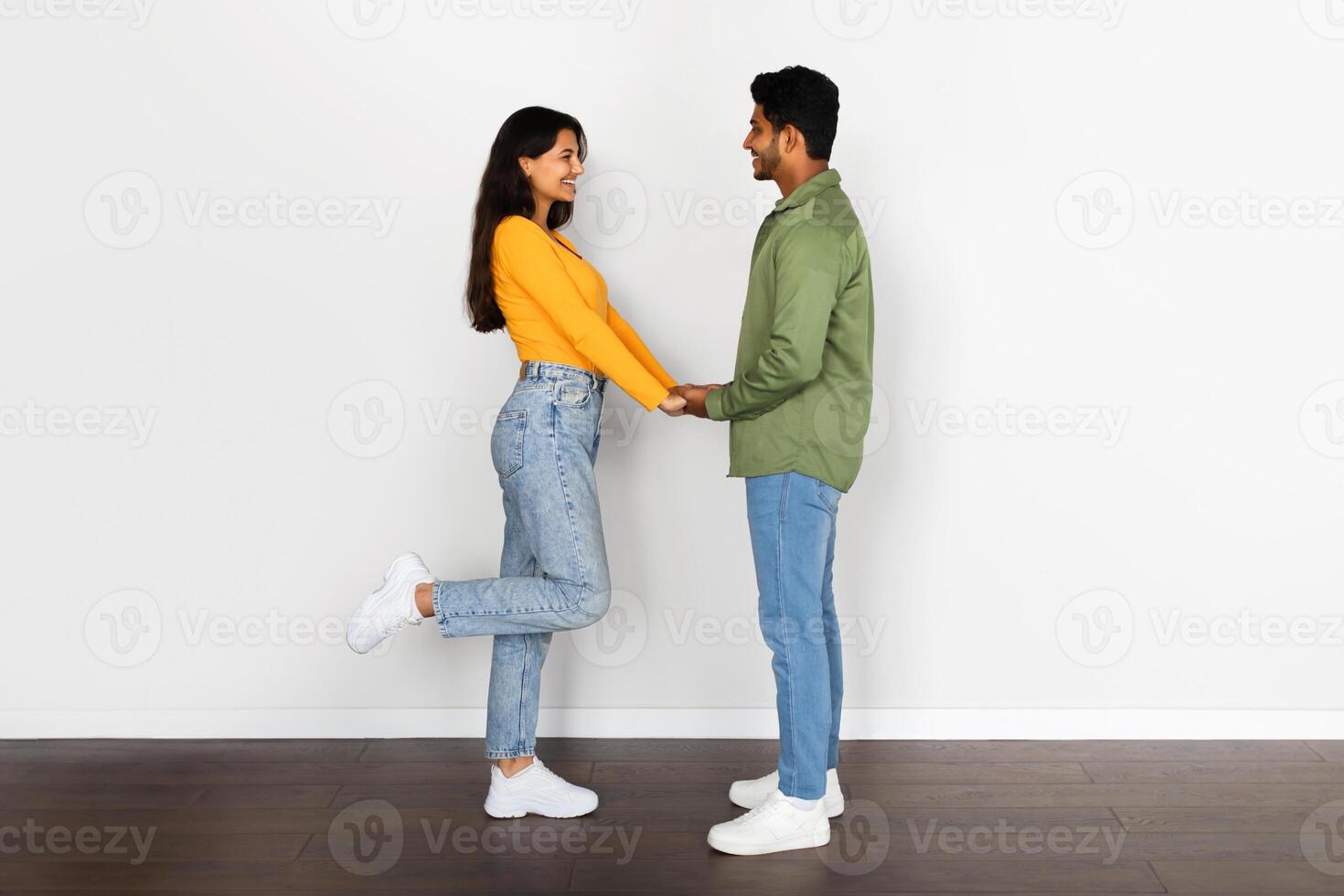 Playful hindu couple holding hands, woman lifting leg, side view photo