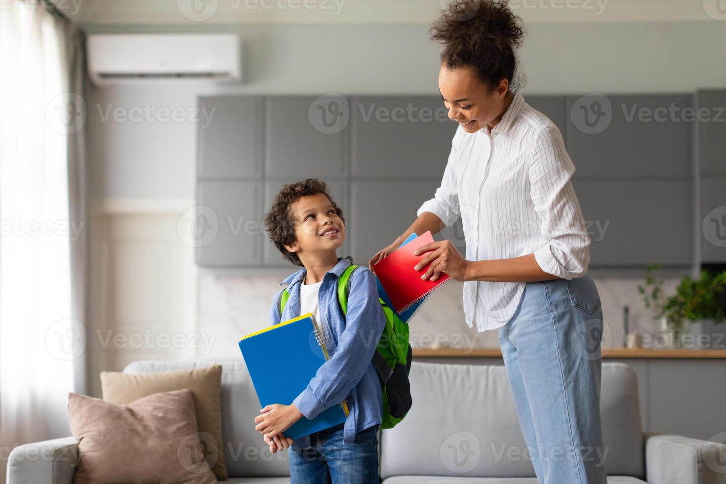 Mother preparing son for school with backpack photo