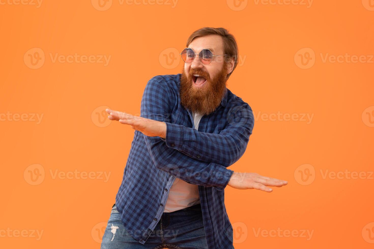 gracioso alegre Pelirrojo hombre con barba en Gafas de sol baile, estudio foto