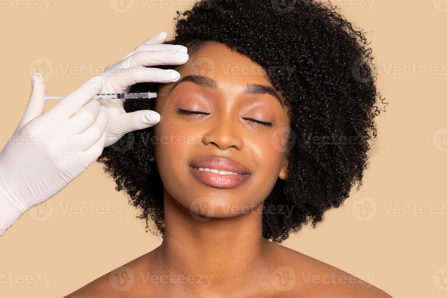 Relaxed black woman with syringe by face, aesthetic care photo