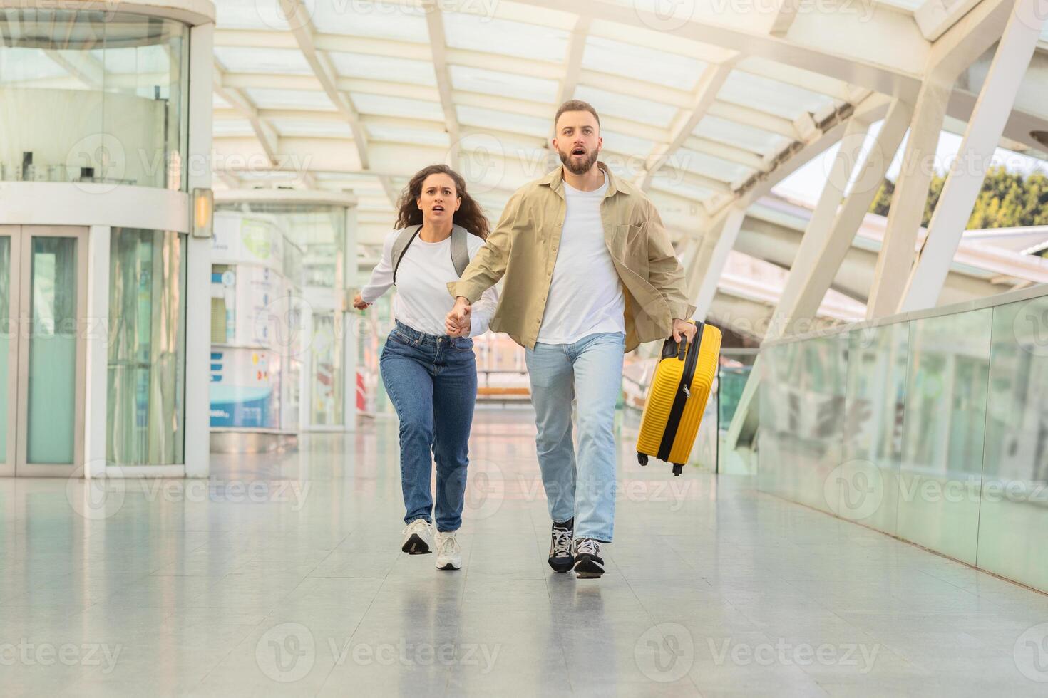 Determined couple sprinting through airport corridor with suitcase, trying to catch flight photo