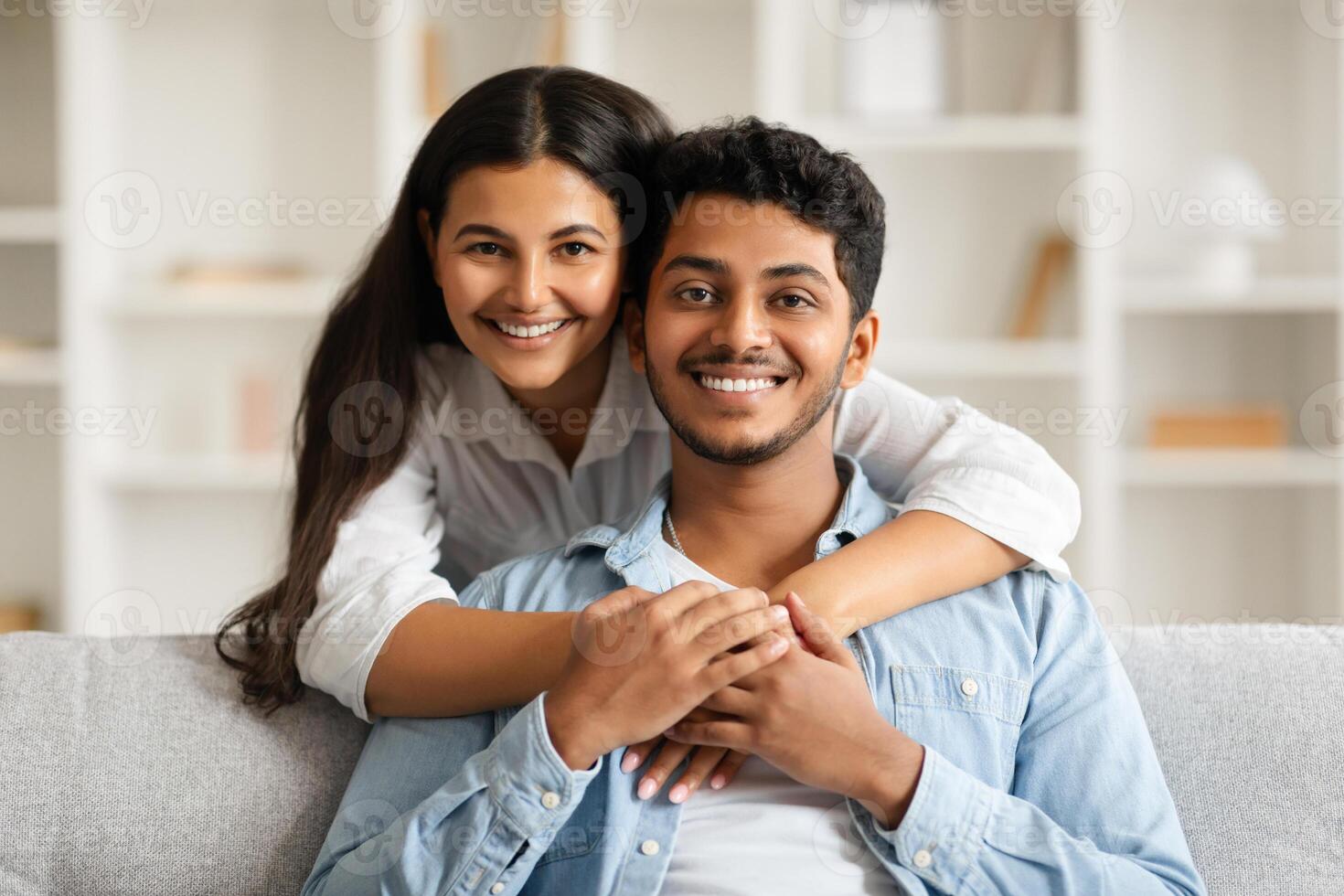 Loving indian couple hugging on sofa with bright smiles photo