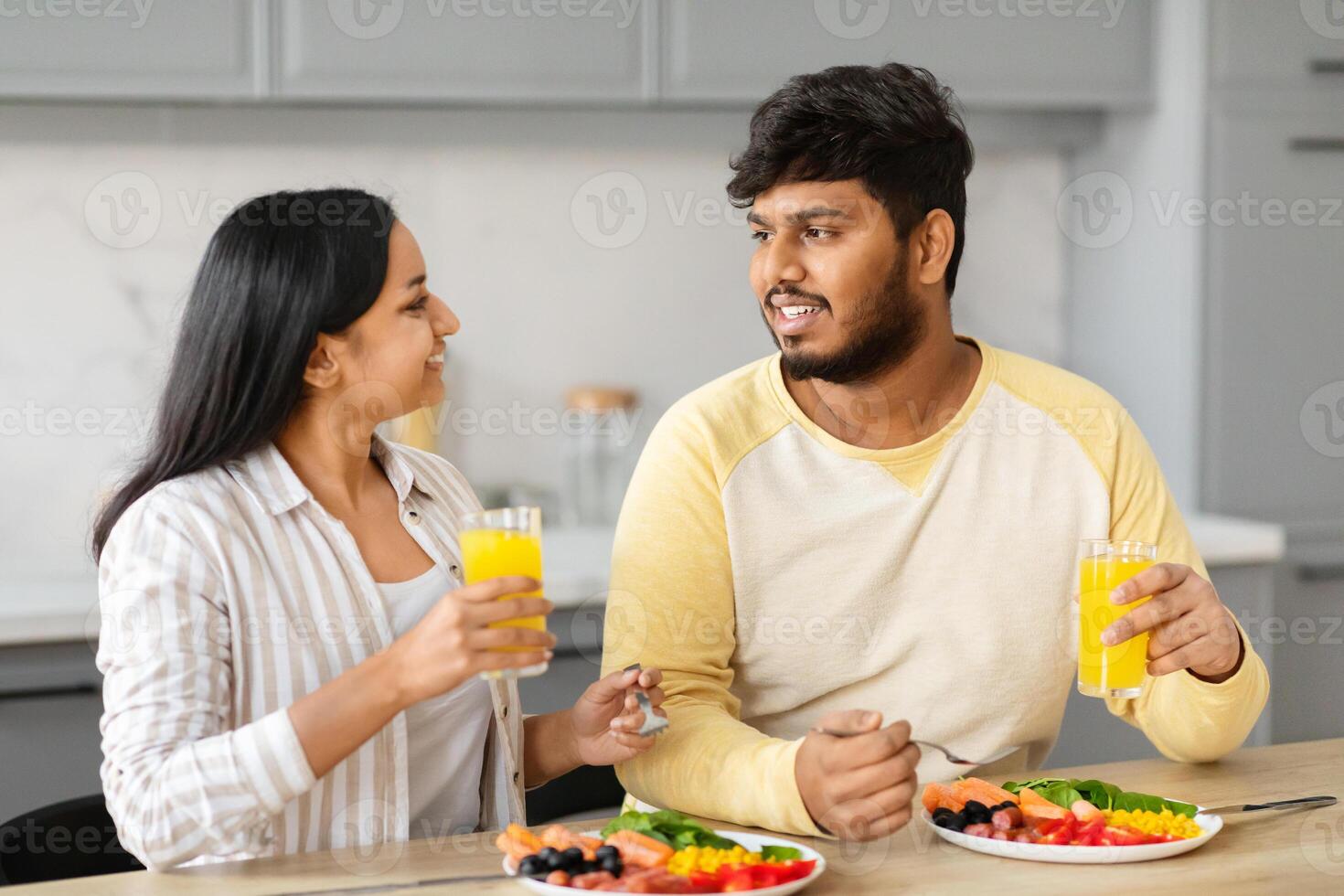 Positive young indian spouses enjoying breakfast together at home photo