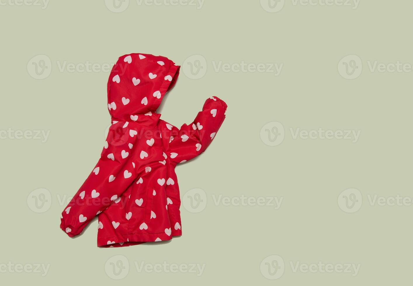 Child's raincoat red color with white heart. Baby girl outwear on blue background photo